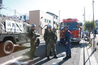 消防車の前で自衛隊員と消防職員が話をしている写真