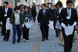 ゴミ袋を持ち、歩いている市長や、新入職員の男女の写真