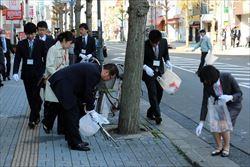 木の周りのゴミを拾う市長や、新入職員の男女の写真