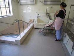 中丸デイサービスセンターのお風呂場に立つ女性の写真