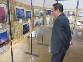 両手を後ろに組んで、すだれに展示されている写真の作品をじっと見ている市長の写真