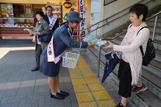 駅の階段から降りて来た女性にチラシを手渡している重田 彩さんの写真