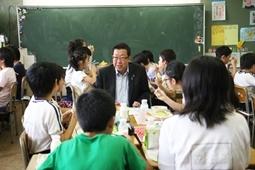 机を向かい合わせにしてグループを作り、市長もグループに加わって子ども達と話しながら給食を食べている写真