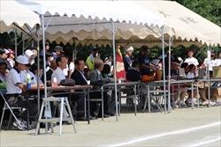 運動場のテントの中に設けられている来賓席に市長や来賓の方々が座っている写真