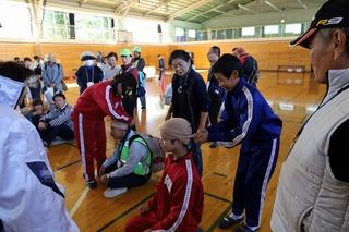 体育館で包帯の巻き方を習っている子供達と、見学している参加者の人を撮影した写真