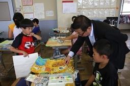 児童が机に広げている絵を指さし質問をしている市長の写真