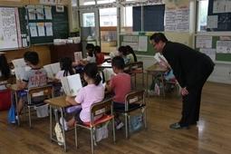 教科書を見ている児童の横で腰を低くしてたち、教科書を覗いている市長の写真