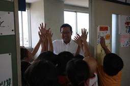 教室からでようとする笑顔の市長とハイタッチをしている子供達の写真