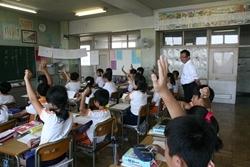 三角小学校にて授業中生徒が手を挙げている様子を見学する市長の写真