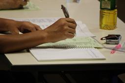 机の上に資料やノートが広げられ、ペンを持っている参加者の写真