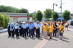 整列する、警察職員と、黄色いシャツや、タスキをつけた関係者の写真