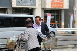 タスキをつけた市長が、笑顔で、自転車を押す女性に挨拶をしている写真