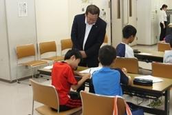 「ふじみ野寺子屋」に参加した男の子2名が着席して学習している様子をそばで見ている市長の写真