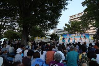 七夕まつりのステージ上でフラダンスの踊りが披露されており、観客席で沢山のお客さんが舞台を見ている写真