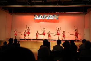 赤いレオタードを着た女性たちがステージでバレエを踊っている写真