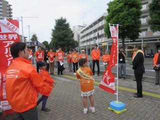 世界アルツハイマーデー街頭キャンペーンに参加されている方々がオレンジ色のジャンパーを着て沿道に集まっており、参加者の中央で市長が話をしている写真