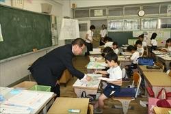教室で、男子生徒が描く絵を指さしながら話す市長の写真