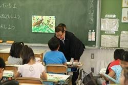 男子生徒の机の前に立ち、中腰で生徒の絵を見る市長の写真