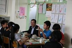 笑顔で、生徒と話しながら、給食を食べる市長の写真