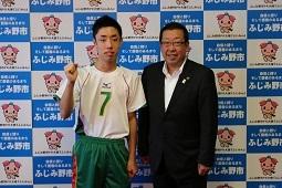 ユニフォームを着た嶋村 司さんが右手でガッツポースをして市長と一緒に写っている写真