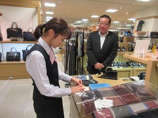 女性店員が包装をしている所を見ている市長の写真