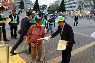 お揃いの帽子を被った市長が街頭で歩いている人にチラシを配っている写真