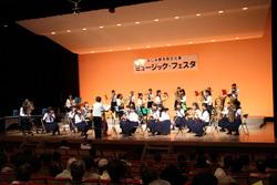ミュージックフェスタの舞台で行われている吹奏楽の演奏を観客が聞いている写真