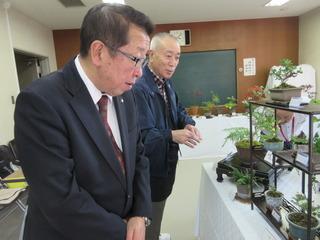 男性の案内を受けながら鉢植えの展示を見学している市長の写真