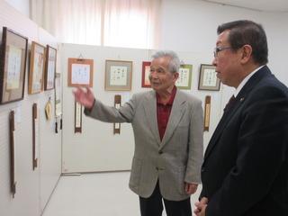 男性の案内を受けながら書道の展示を見学している市長の写真