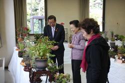 鉢植えの花が並ぶ机の前で話しをしている市長と女性2名の写真