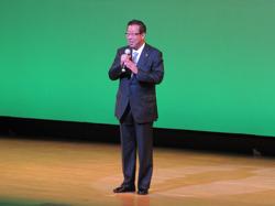 芸能発表会カラオケの部の会場の舞台で市長がマイクを持って話をしている写真