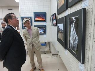 壁に飾られた写真の作品を見ている市長の写真
