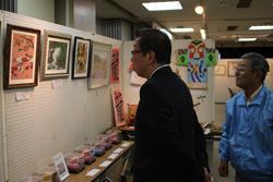 いきいきクラブ連合会作品展示会にて、ボードに展示されている額に入った絵画の作品を市長がじっくり見ている様子の写真