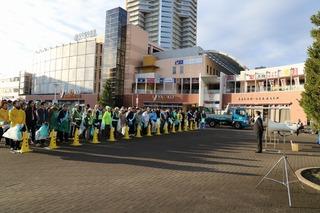 清掃活動へ参加する方々がごみ袋を手に持って黄色いポールの前に整列している写真