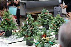 装飾された小さなクリスマスツリーが机の上に並べられている写真