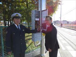 信号の電源スイッチに手を置く市長と、警察職員の男性の写真