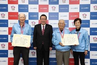 青いジャンパーを着た上福岡一丁目寿会の選手の方3名が首からメダルを下げ、賞状を手に持って、市長と笑顔で写っている写真