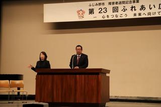 演壇に立ち挨拶をしている市長とその横で手話で通訳をしている女性の写真