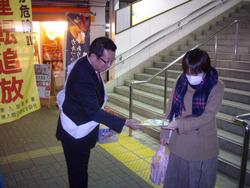 市長が、駅の階段から降りて来た女性に、冬の交通事故防止運動のチラシを手渡している写真