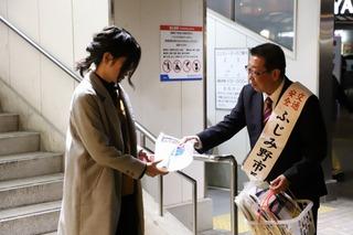 駅の階段を下りて来た女性にチラシを手渡している市長の写真