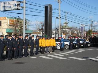 警察署の駐車場に3台のパトカーと警察官が整列している写真