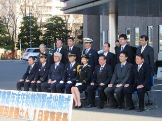 市長と飯田 里穂さん、警察官、スーツを着用した関係者の方々の集合写真