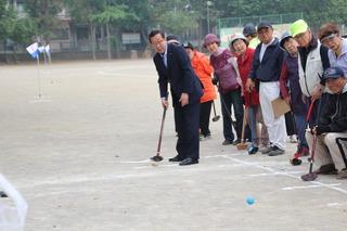 グラウンド・ゴルフのクラブを持ち、ボールを打った市長を参加者の方々が見ている写真