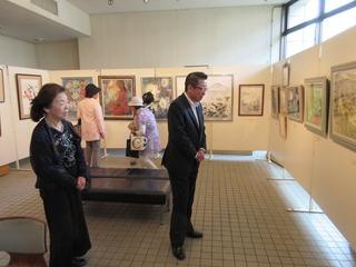 日本画連盟展にて壁に飾られた作品を鑑賞する市長と来場者の写真