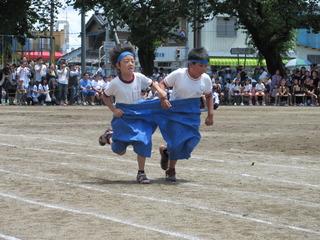 青い大きなズボンの片足に一人ずつ児童が入ってコースを走っている写真