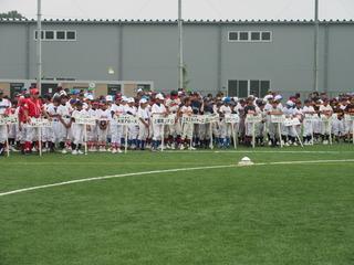 少年野球大会に参加する選手たちがチームのプラカードの前に整列して並んでいる写真