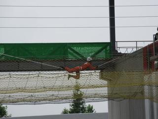 建物の間の高所にロープと網のようなものが張られており、一人の消防隊員がロープを伝っている訓練の写真