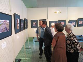 壁に飾られた写真展のいろいろな写真を見ている市長達の写真