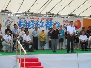おおい祭りの舞台上でたくさんの関係者の方々がいる中、挨拶している市長の写真