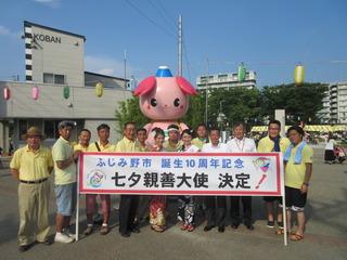 七夕まつりの会場でスタッフが横断幕を持って記念撮影している写真